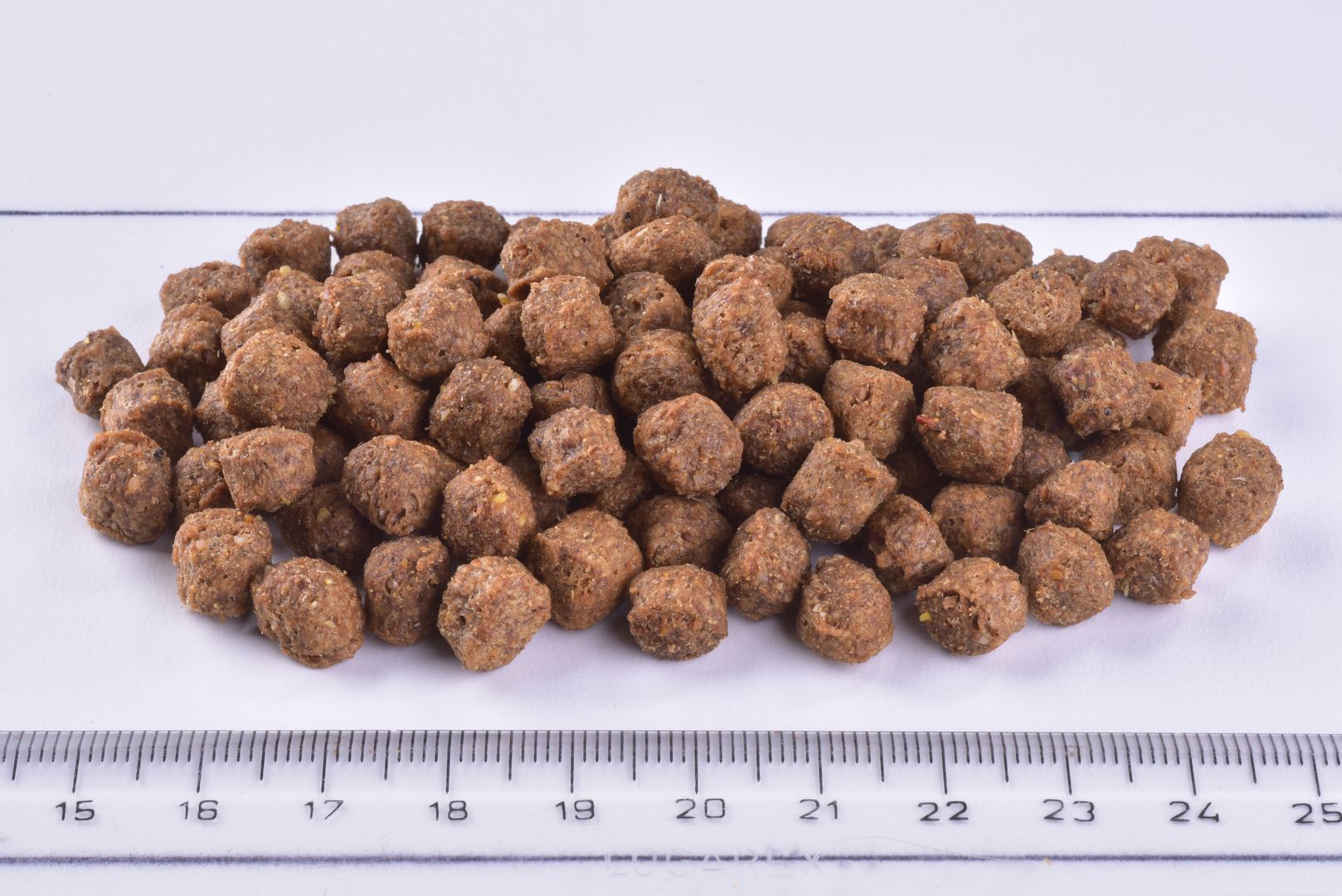 Brit Premium Dog Dry Food Adult Small Kibble on a white surface with a ruler for scale.