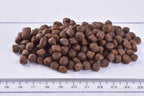 group of Brit Premium Dry Kitten Food kibbles  with a ruler for scale on a white background